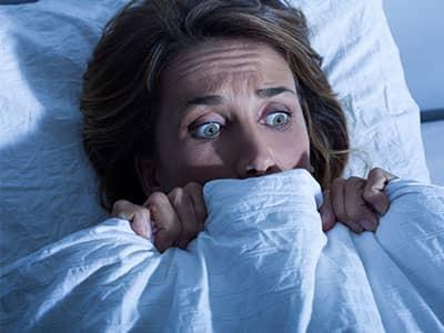 lady with sheet pulled up to her face because of creepy bugs